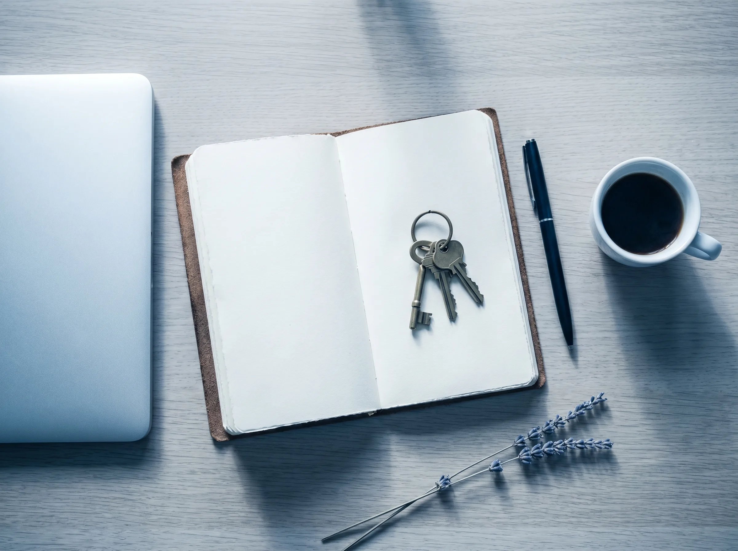 Trousseau de clés posé sur un cahier ouvert à côté d'un laptop fermé, ambiance bureau bleuté symbolisant l'accès retrouvé